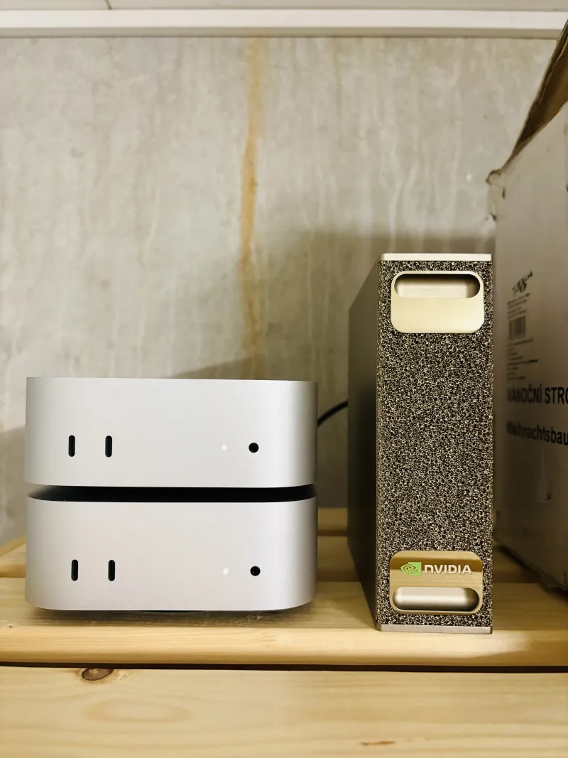 The NVIDIA DGX Spark (right) on a wooden shelf, next to two stacked Mac minis for scale